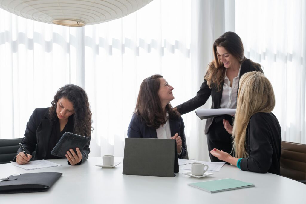 Group of four businesswomen collaborating around a table in a bright office.