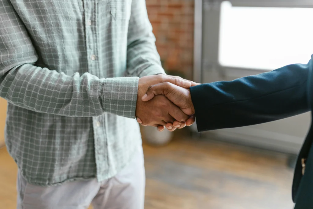 Casual and formal dressed individuals shaking hands in a bright room.