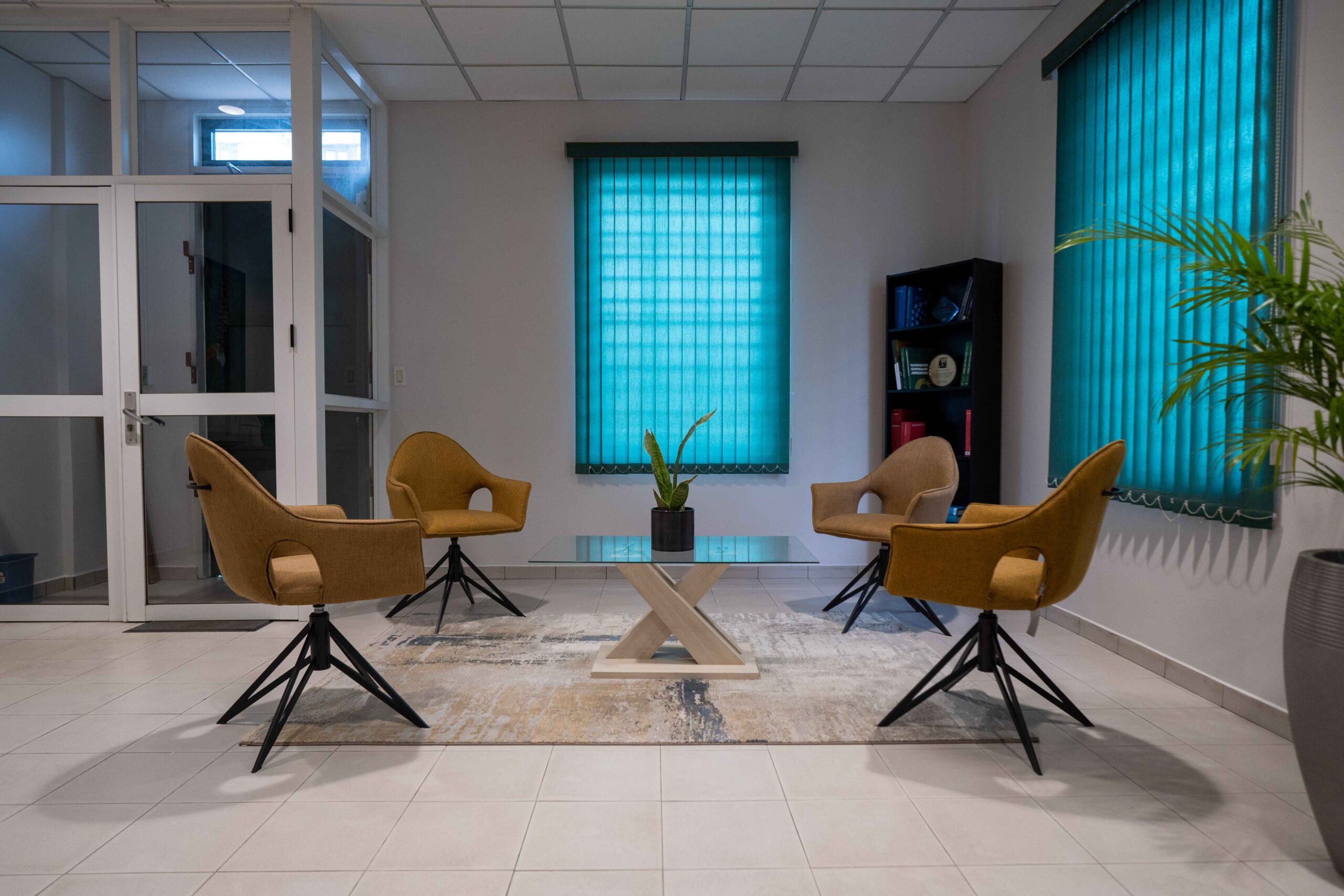 Modern office lounge area with four chairs around a glass table.